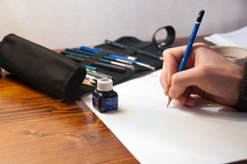 mano che disegna con matita e china