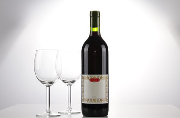 A bottle of wine with blank label and two emtpy wine glasses