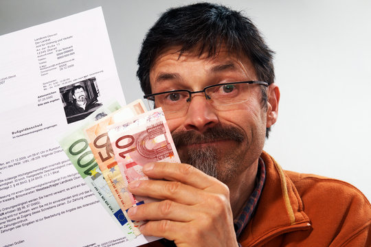 man holding a speed ticket fine and paper money