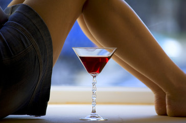 Beautiful girl legs and a glass of alcoholic beverage