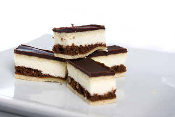 pieces of a chocolate cake with white cream on a plate in shallo