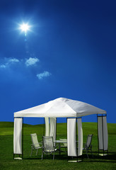 chairs and table under white picnic tent on green grass