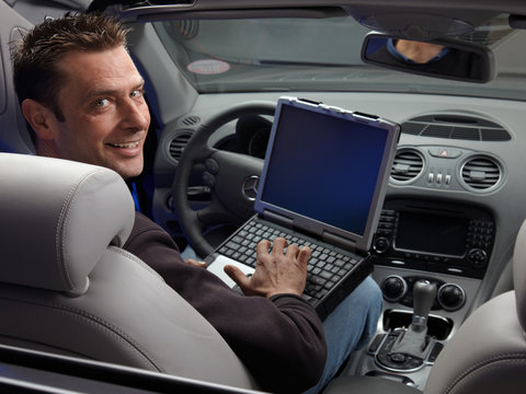 Master mechanic with his diagnostic computer sitting in open car