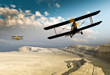 Two vintage WWI double wing biplanes flying over canyon