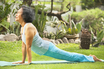 Senior old woman doing yoga in park