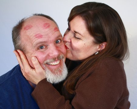 Woman with red lipsick kissing man.