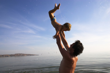 father is tossing up a child in water