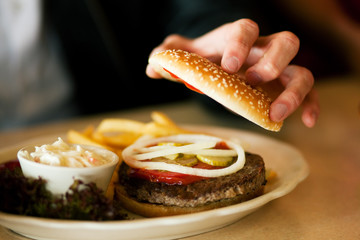 Mann im Restaurant isst Hamburger - obrazy, fototapety, plakaty