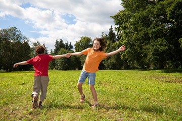 Kids running, jumping on green meadow