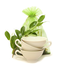 Fototapeta na wymiar porcelain cups, green leaves and a bag of tea