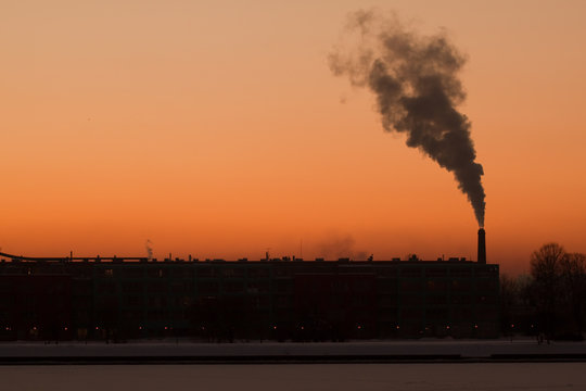 Smoke rising from factory at sunset