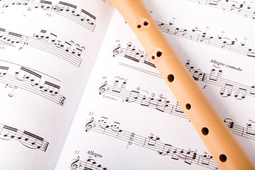 Wooden flute on sheet music. Close up.