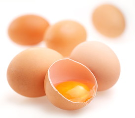 Brown eggs on a white background. One egg is broken.