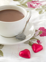 Cup of cappuccino with two red  chocolate hearts