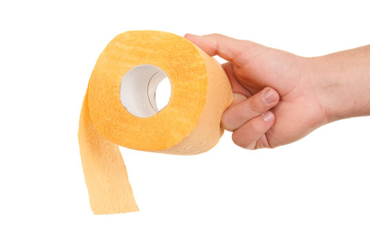 Hand Holds Roll Of Yellow Toilet Paper