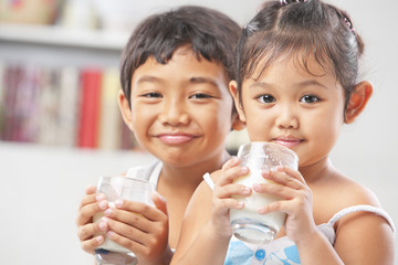 Two little girl and boy each holding glass of milk