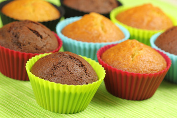 Muffins in colorful silicon moulds on green background