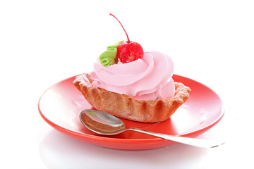 Pink cheesecake with maraschino cherry on the plate