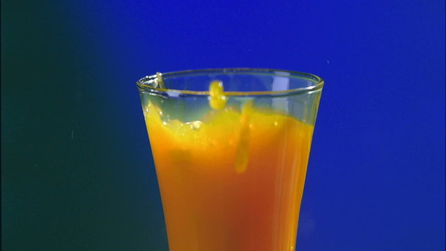 Orange slices falling into the juce. Slow motion 35mm shot.