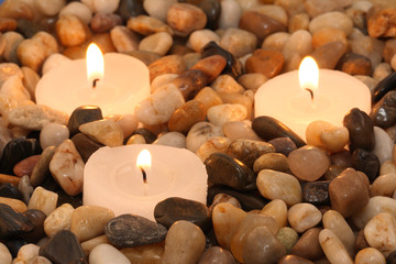 Three candles burning between stones in a spa.