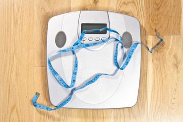 Modern electronic scales with blue tape measure across it