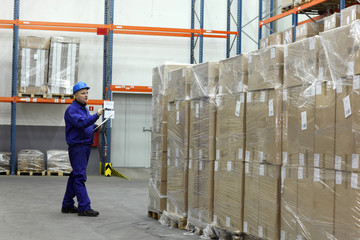 worker in blue uniform counting stocks in warehouse