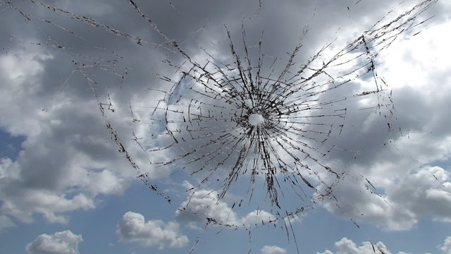 Broken window, cracked glass against sky time lapse