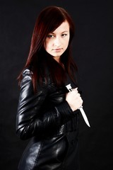 Woman in black holding a knife - dark background