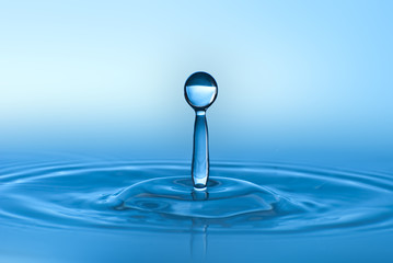 Fototapeta na wymiar Clean blue drop of water splashing in clear water. Abstract blue