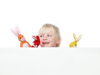 Little girl with coloured finger hares looks over a white wall