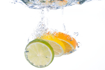 Slices of citrus fruit falling into clear water