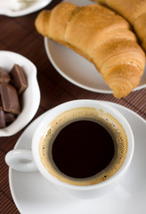 Black coffee served with croissant