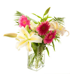 a bunch of lilies and gerberas in the transparent vase on the w