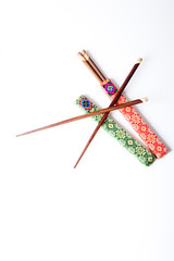 Two pairs of wooden chopsticks in red and green covers isolated