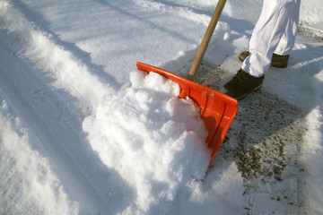shoveling snow with an orange snow shovel
