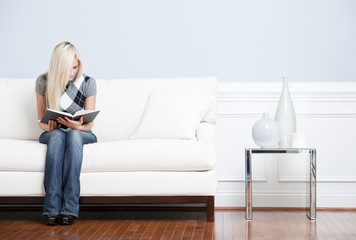 Young Woman Sitting on Sofa Reading