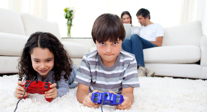 Adorable siblings playing video games lying on the floor