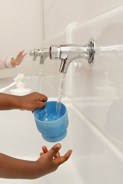 enfant laissant couler de l'eau au robinet