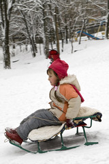 The little girl sledding down a hill