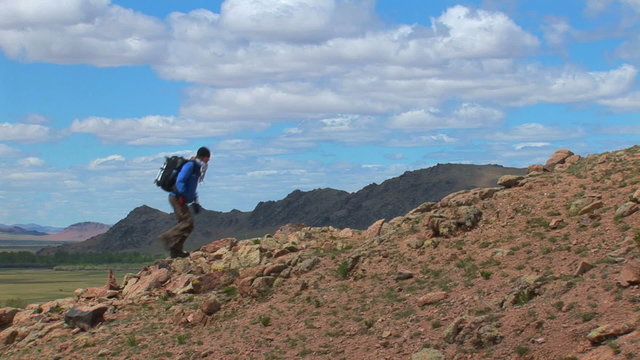 A hiker walks up a mountain.