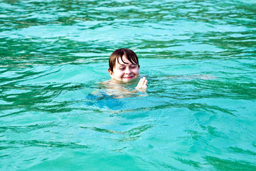 young happy boy with brown hair enjoys  the beautiful sea