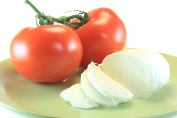 slice of mozzarella and tomato in green plate isolated on white