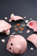 Broken piggy bank containing few coins.