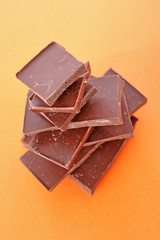 Stack Of Dark Chocolate Pieces,  Over Orange Background