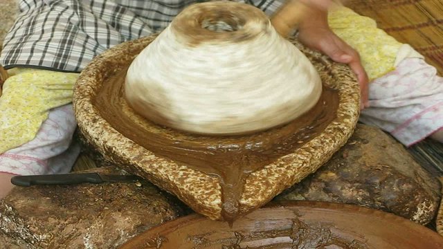 MUJER MOLIENDO EL FRUTO DEL ARBOL DE ARGAN