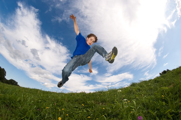 Boy jumping, running against blue sky