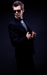 elegant young man wearing suit, bow tie and sunglasses