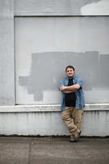 Portly man next to concrete wall.