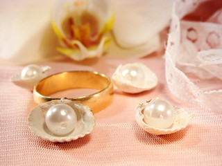 Fototapeta na wymiar złota obrączka na różowej satyny z orchidei i perłami