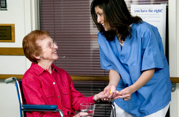 Nurse giving senior woman pills
